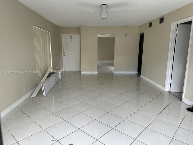 spare room featuring a textured ceiling, ceiling fan, and light tile patterned flooring