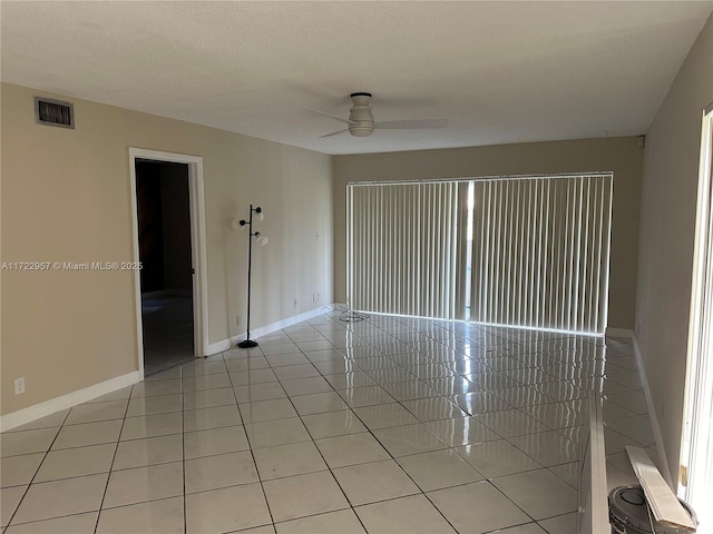 tiled spare room with ceiling fan