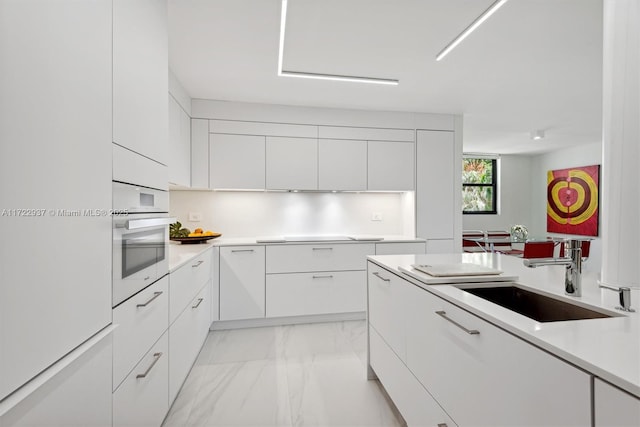 kitchen with white oven, sink, and white cabinets