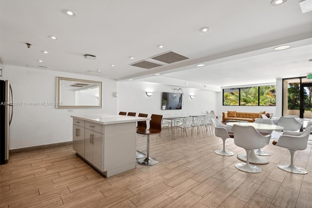 kitchen with stainless steel fridge, white cabinetry, a large island, and a breakfast bar area