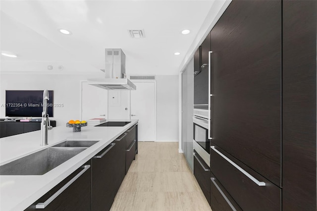 kitchen with black electric stovetop, wall oven, island range hood, and sink