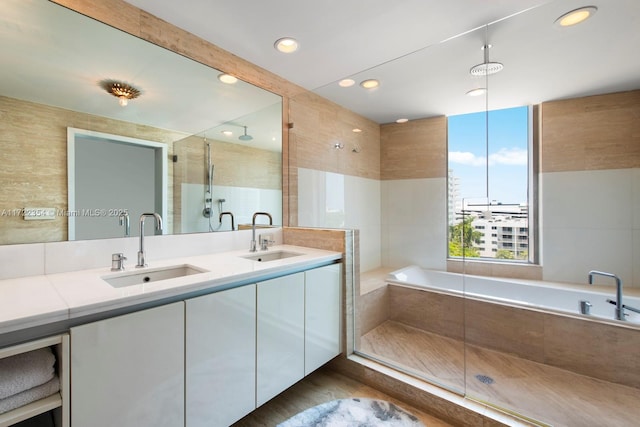 bathroom featuring plus walk in shower, vanity, and tile walls