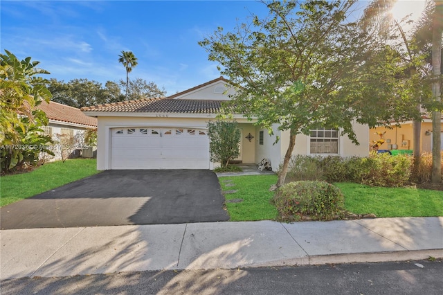 view of front facade featuring a garage, aphalt driveway, a front lawn, and stucco siding