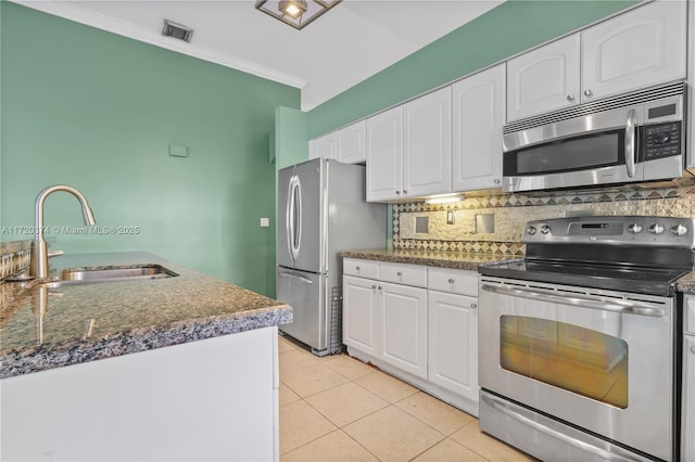 kitchen with appliances with stainless steel finishes, sink, light tile patterned floors, and white cabinets