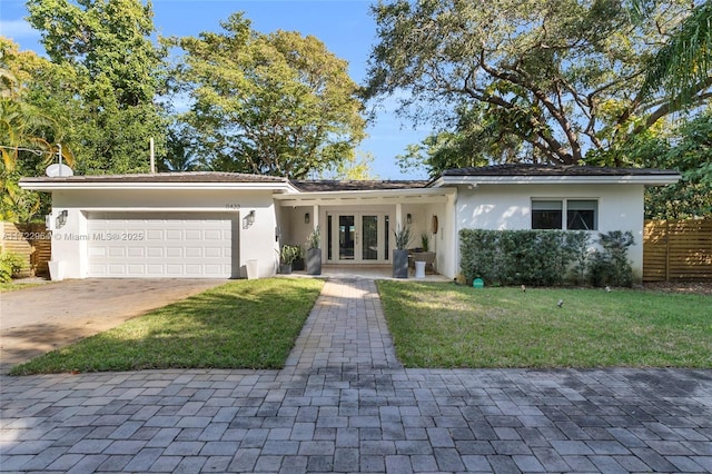 ranch-style house with a front lawn, a garage, and french doors