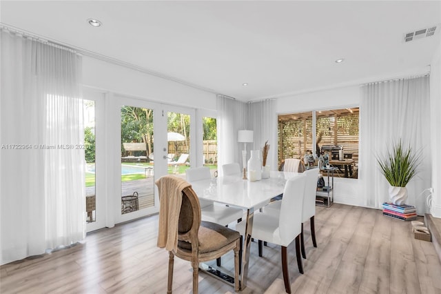 dining space with light hardwood / wood-style floors, crown molding, and french doors