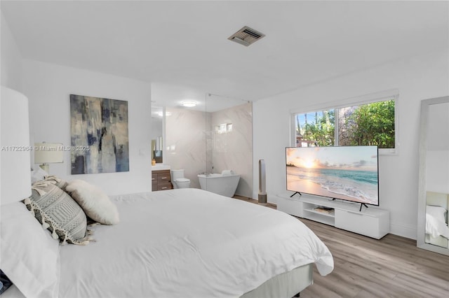 bedroom with ensuite bathroom and wood-type flooring