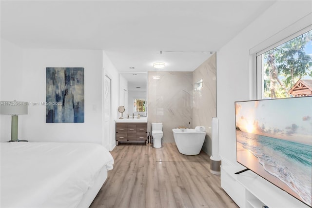 bedroom featuring light wood-type flooring, tile walls, and sink