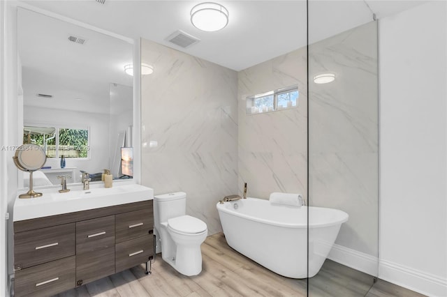 bathroom with vanity, hardwood / wood-style flooring, a washtub, toilet, and tile walls