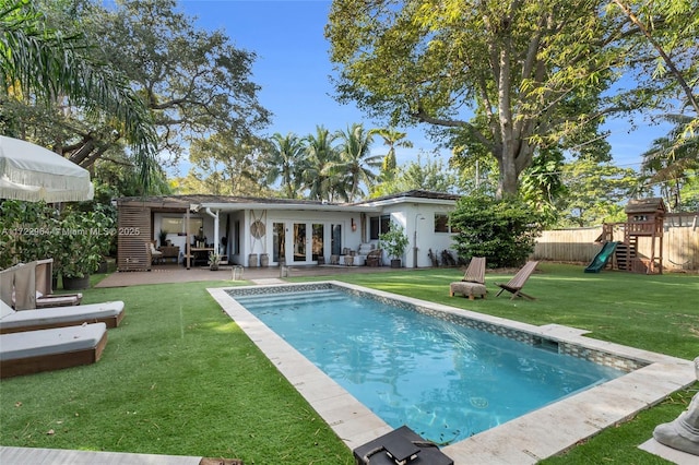 view of pool featuring a patio area, a playground, a yard, and french doors