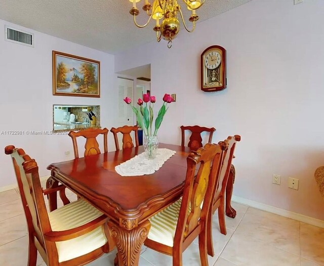 tiled dining area featuring a textured ceiling and a notable chandelier