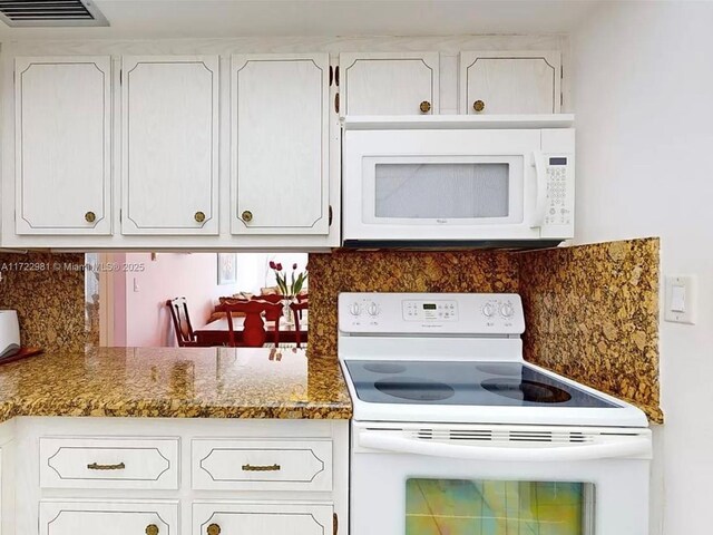 kitchen featuring white appliances, white cabinetry, dark stone countertops, and backsplash