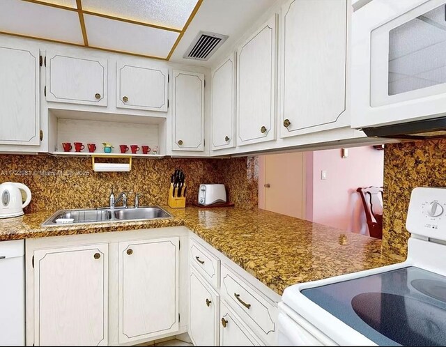 kitchen featuring backsplash, white cabinetry, sink, and white appliances