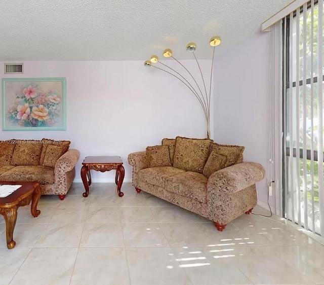 living room featuring a textured ceiling, light tile patterned floors, and visible vents