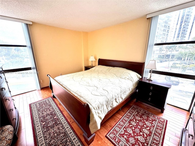 bedroom featuring a wall of windows, light wood-style flooring, and a textured ceiling