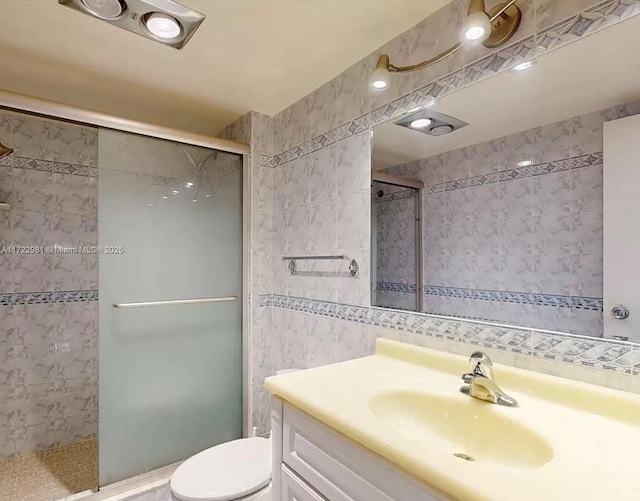 bathroom with an enclosed shower, vanity, toilet, and tile walls