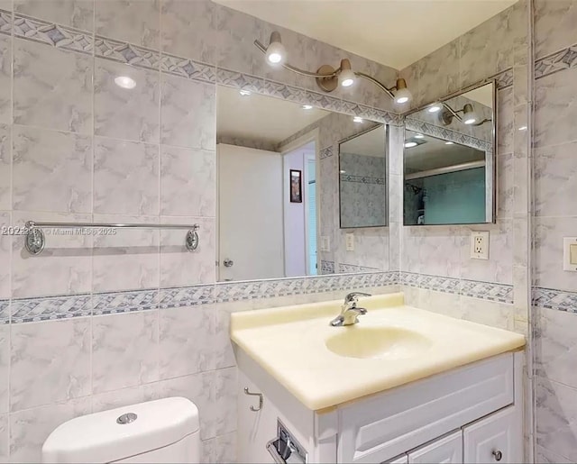 bathroom with toilet, tile walls, and vanity