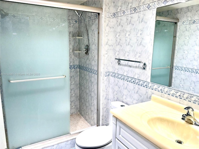 full bath featuring toilet, a shower stall, tile walls, and vanity