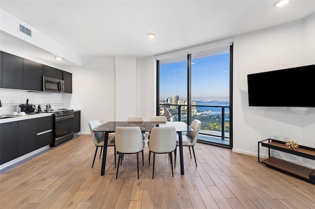 dining space with floor to ceiling windows and light wood-type flooring