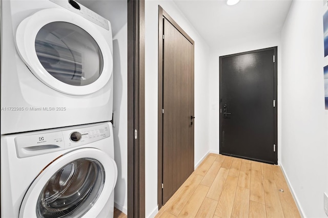 laundry area with light hardwood / wood-style flooring and stacked washing maching and dryer