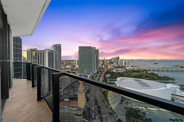 balcony at dusk featuring a water view