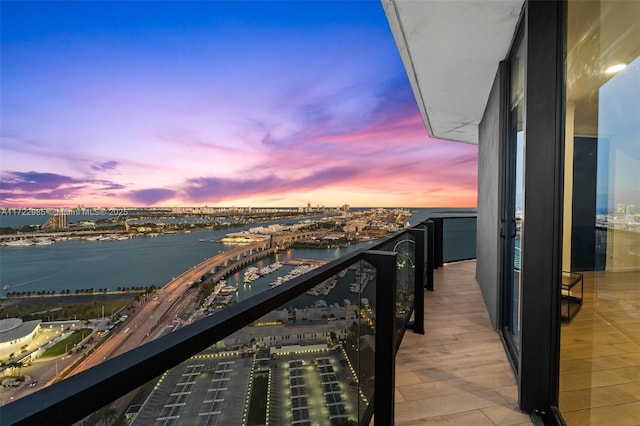 balcony at dusk featuring a water view