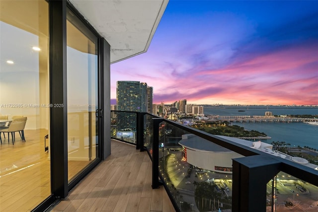 balcony at dusk featuring a water view