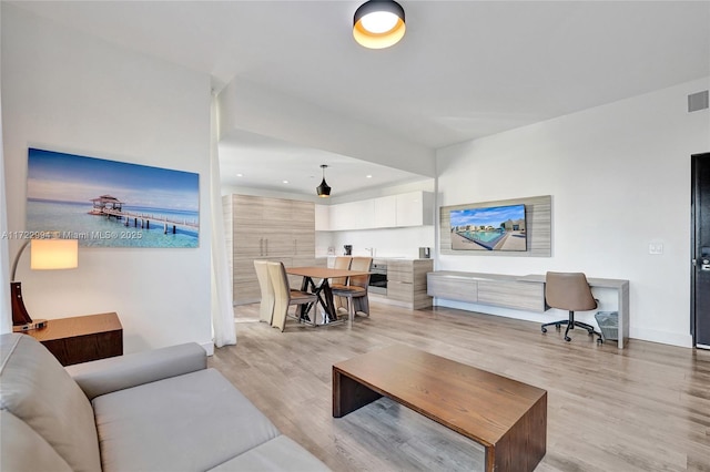 living area with light wood-style floors, visible vents, baseboards, and recessed lighting