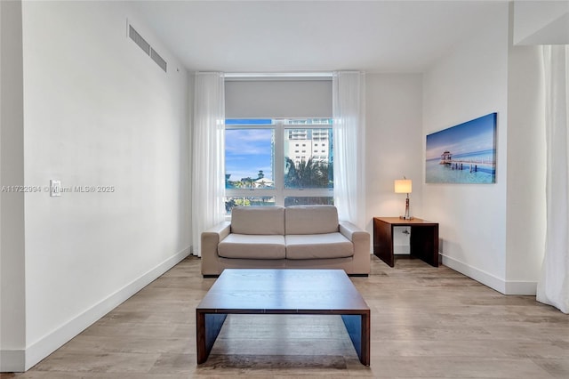 living room with light wood-style flooring, visible vents, and baseboards