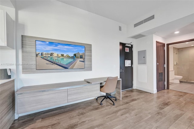 home office featuring electric panel, visible vents, and wood finished floors