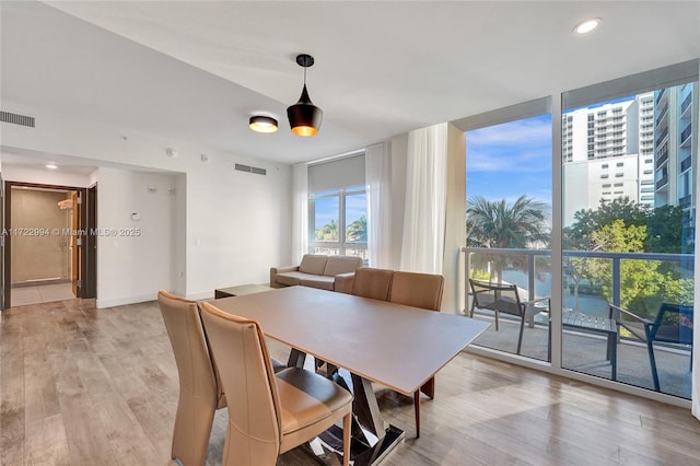 dining area with light wood-type flooring, floor to ceiling windows, visible vents, and recessed lighting