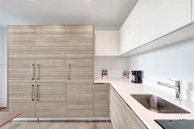 kitchen featuring light countertops, modern cabinets, a sink, and white cabinets