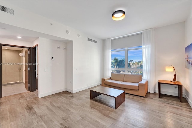 living area featuring light wood-style floors, baseboards, and visible vents