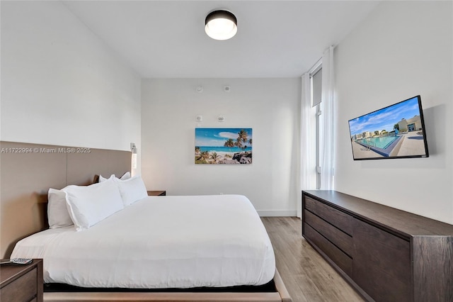 bedroom with light wood finished floors and baseboards