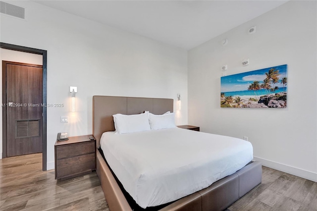 bedroom with light wood-style flooring, visible vents, and baseboards