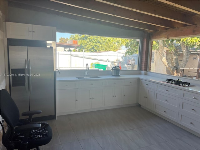 kitchen featuring wooden ceiling, white cabinets, sink, stainless steel fridge, and gas stovetop