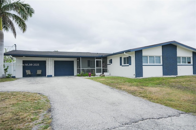 view of front of house with an attached garage, stucco siding, aphalt driveway, and a front yard