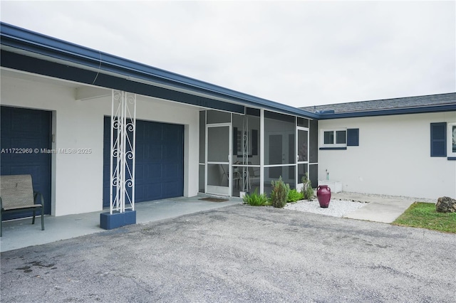 doorway to property with aphalt driveway and stucco siding