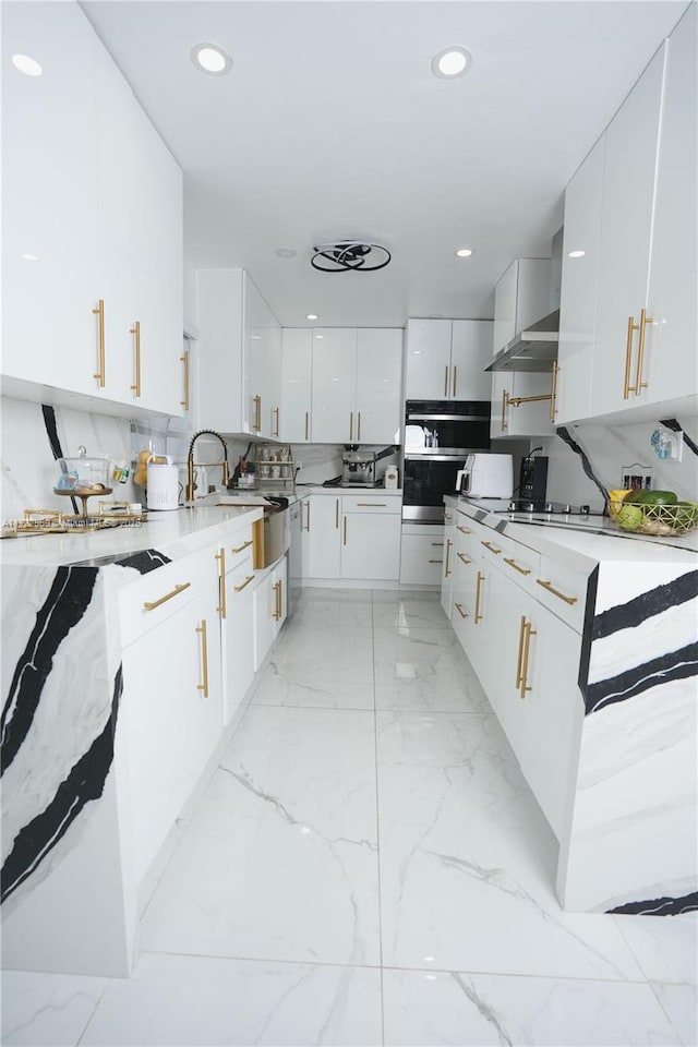 kitchen with white cabinets, light countertops, decorative backsplash, wall chimney exhaust hood, and modern cabinets