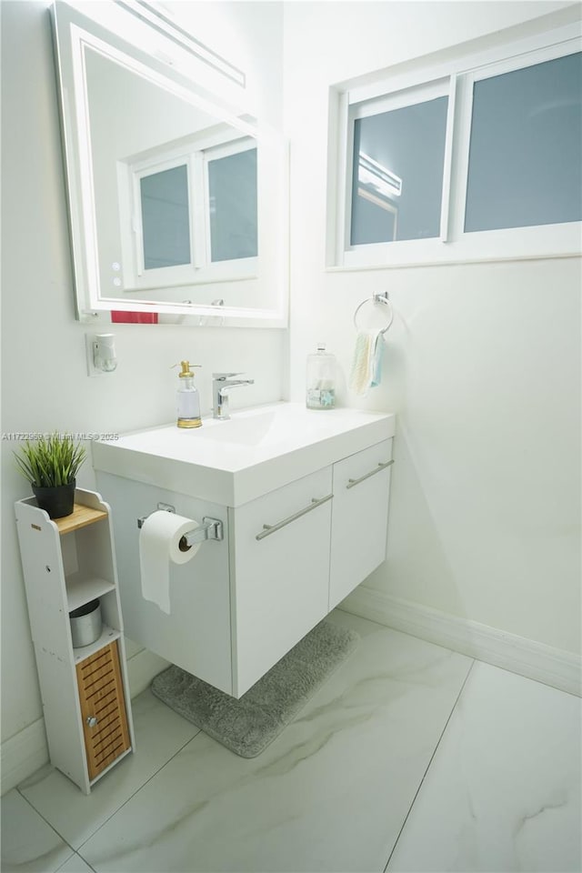 bathroom featuring marble finish floor, vanity, and baseboards