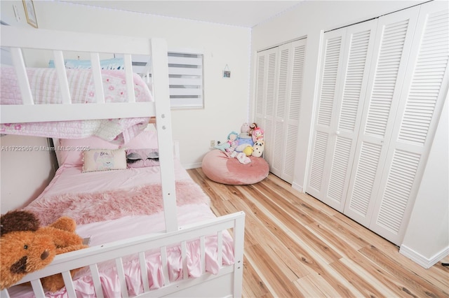 bedroom featuring baseboards, two closets, and wood finished floors