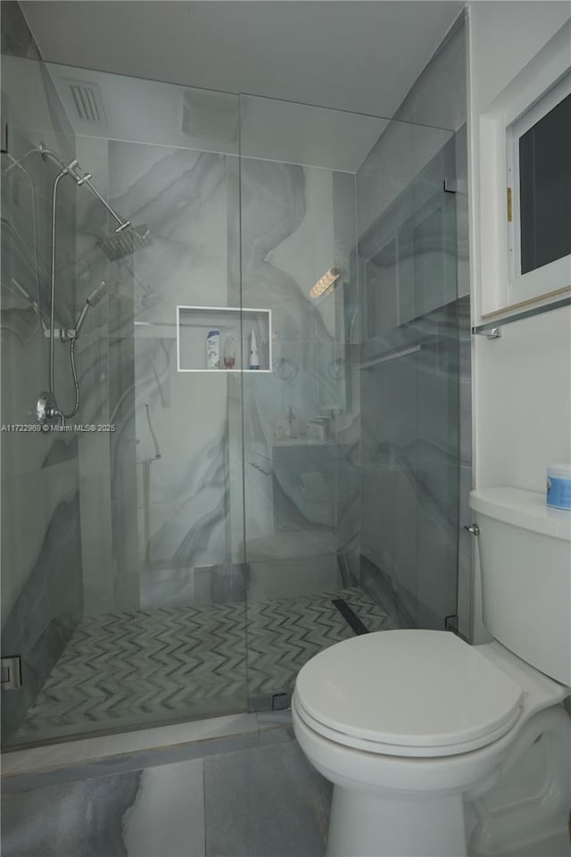 bathroom featuring a stall shower and toilet