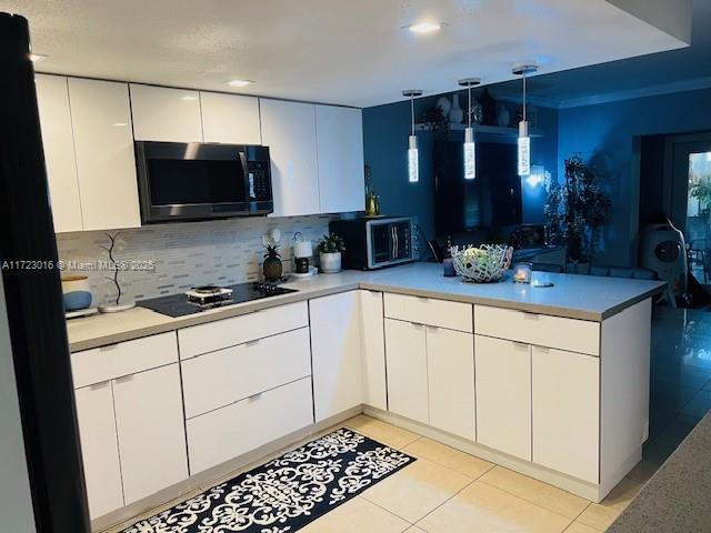 kitchen featuring light tile patterned flooring, pendant lighting, white cabinetry, backsplash, and black electric stovetop