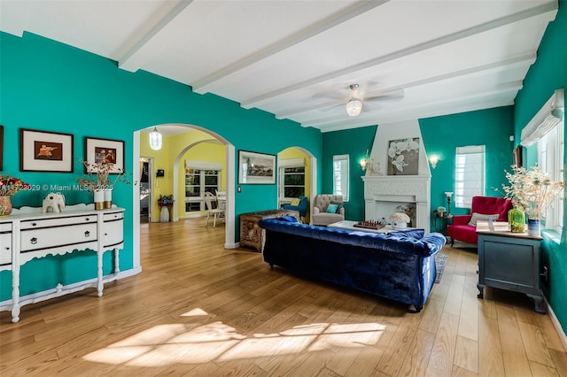 living room with ceiling fan, beamed ceiling, and light wood-type flooring