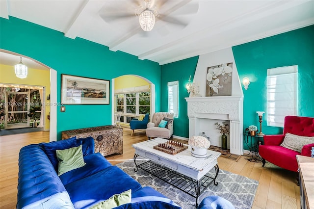 living room with beamed ceiling, light hardwood / wood-style floors, and ceiling fan