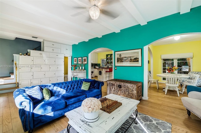 living room featuring beamed ceiling, light hardwood / wood-style flooring, and ceiling fan