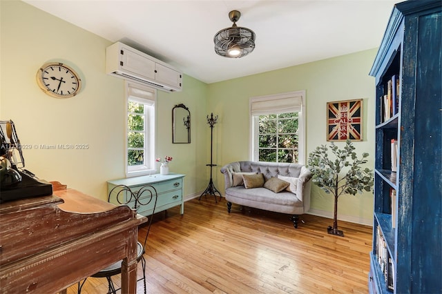 sitting room with light wood-type flooring and a wall unit AC