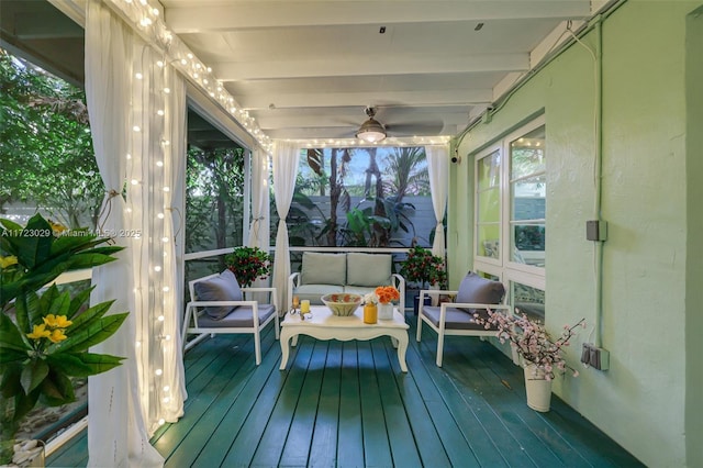 sunroom with ceiling fan and beam ceiling