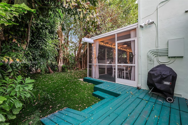 wooden terrace with a sunroom, area for grilling, and a yard