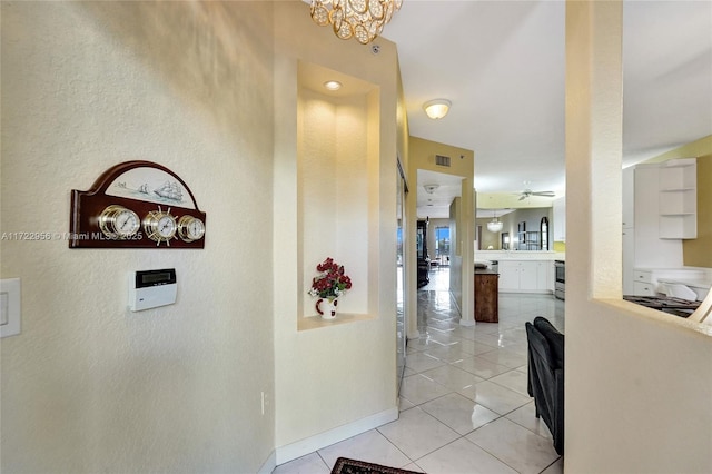 hallway featuring a notable chandelier and light tile patterned flooring